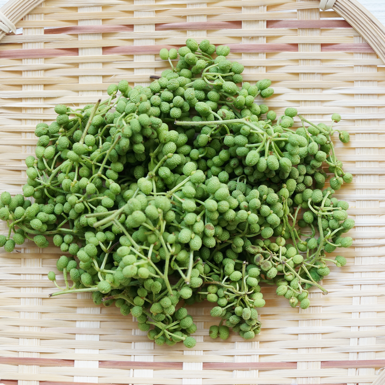 Fresh green sansho berries on a bamboo tray