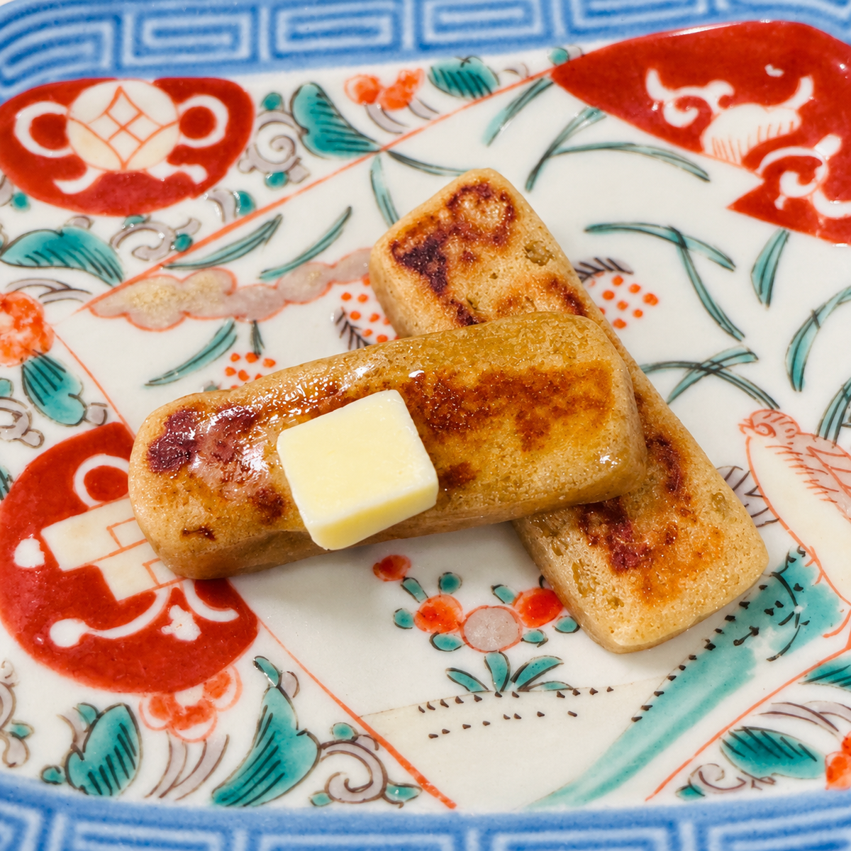Toasted kankoro mochi with a pat of butter on top, on a patterned plate